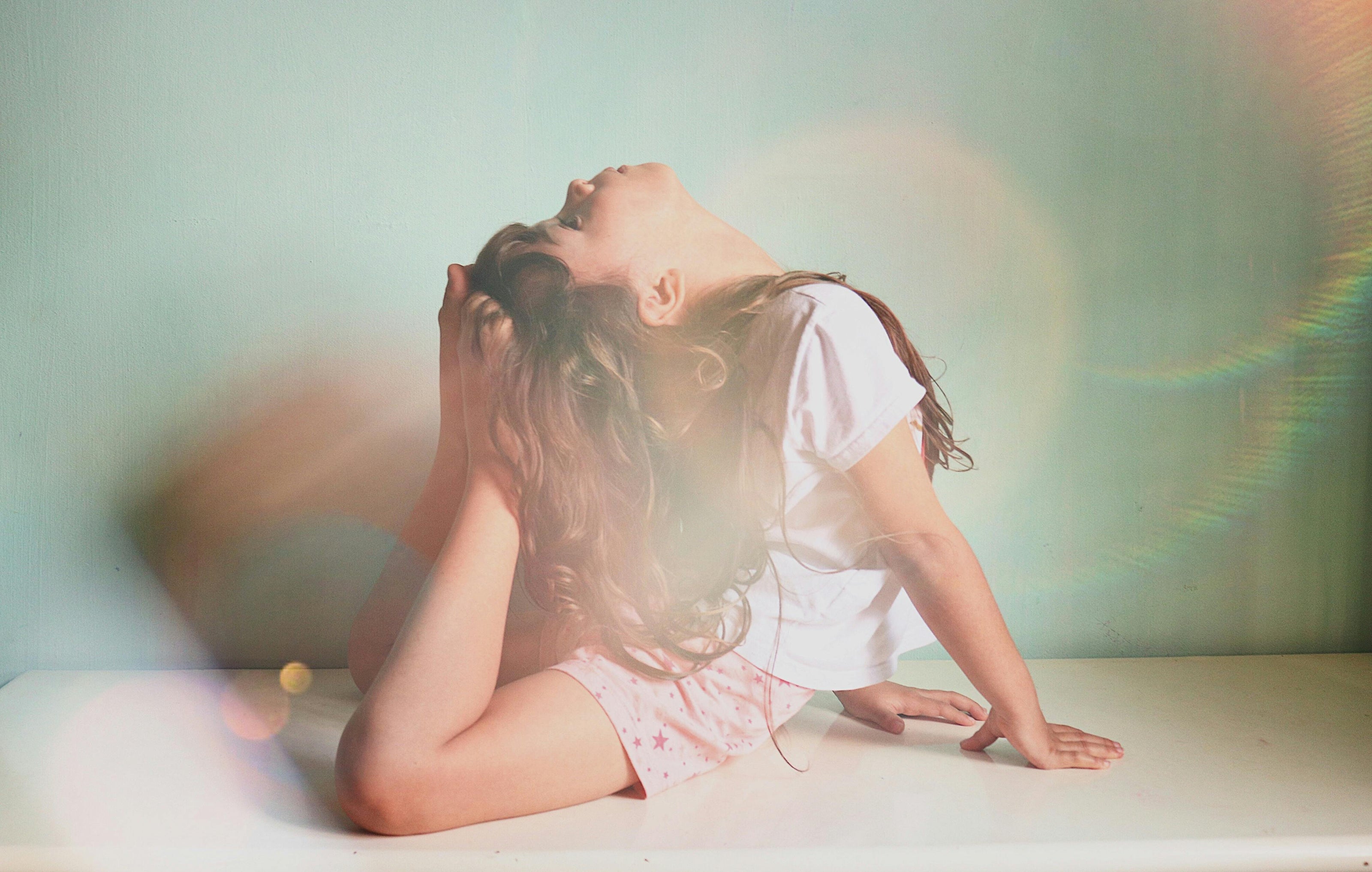 A little girl in a yoga stretching pose with her belly on the floor and her feet touching the top of her head